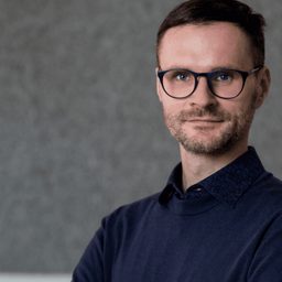 Portrait of Falk Zakrzewski with glasses and a dark shirt.
