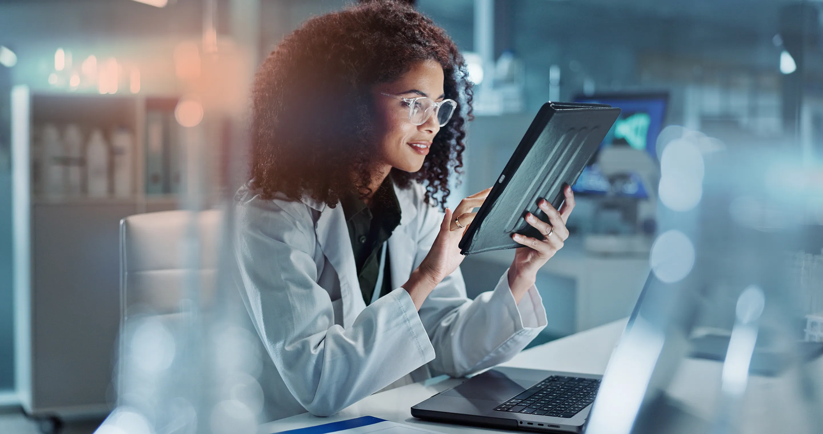 A scientist with a tablet at a laboratory workstation.