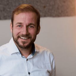 Portrait of Nicolaus Widera, smiling, in a white shirt.