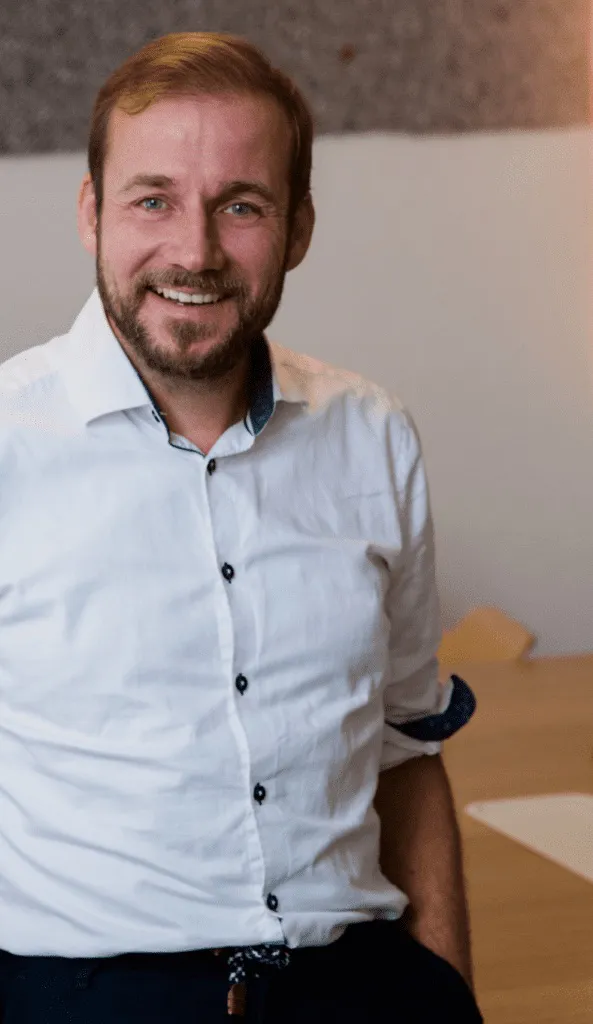 Portrait of Nicolaus Widera, smiling, in a white shirt.