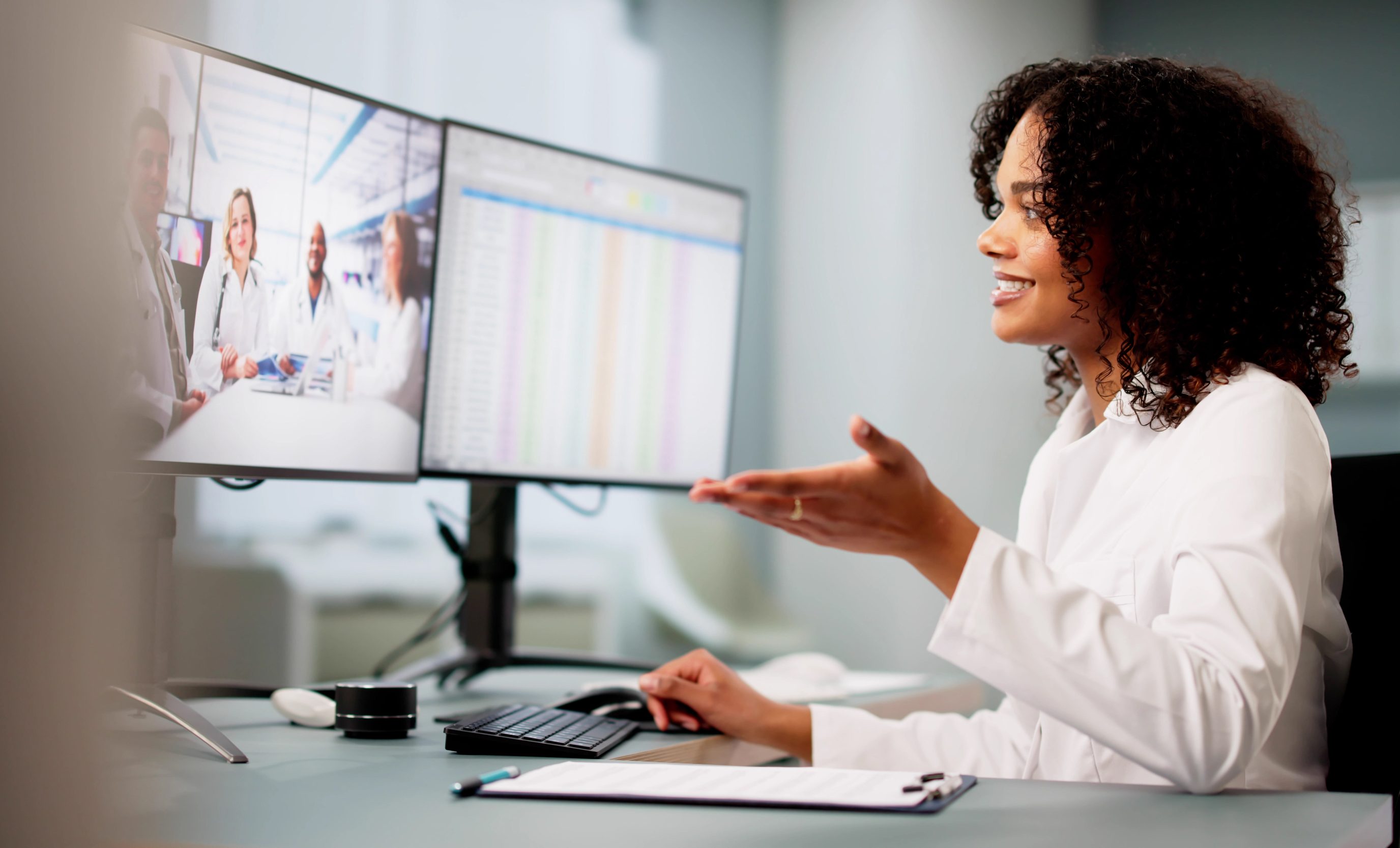A scientist in gloves works at a microscope workstation with a tissue image on screen.