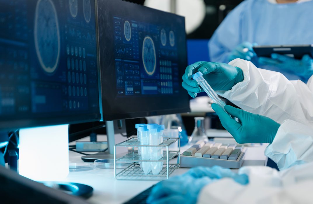 Two scientists in a lab analyze tissue data on a computer screen.